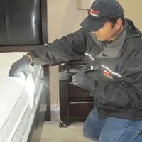 Bed bug inspection technician checking a mattress and bed frame for signs of infestation in Columbus, GA
