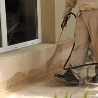General pest control technician spraying exterior perimeter around a home in Columbus, GA