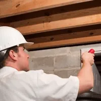 Termite inspection technician checking a basement wall and framing for termite activity in Columbus, GA